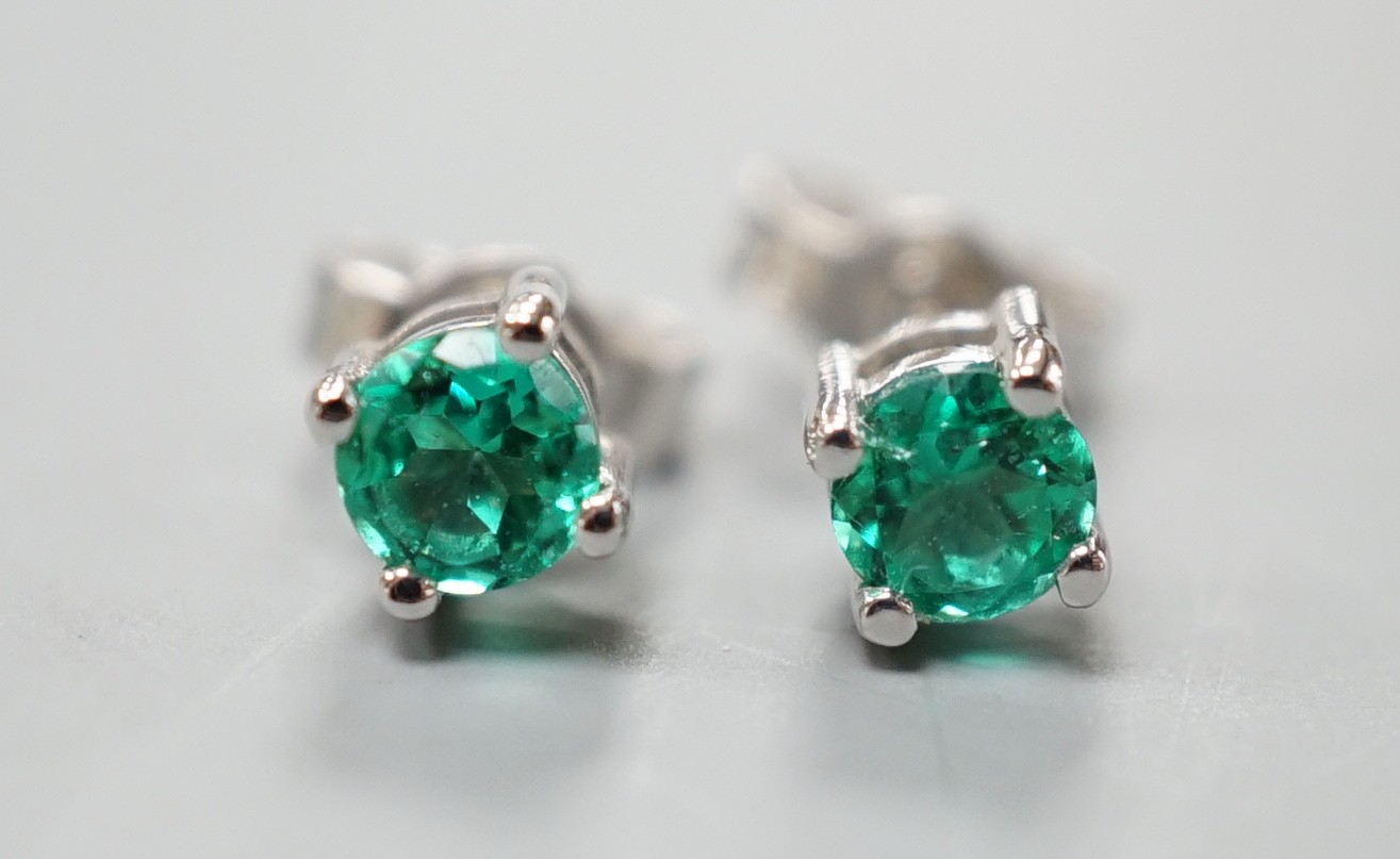 A pair of 750 white metal and solitaire emerald set ear studs, gross weight 1.5 grams, stone diameter approx. 4.2mm.